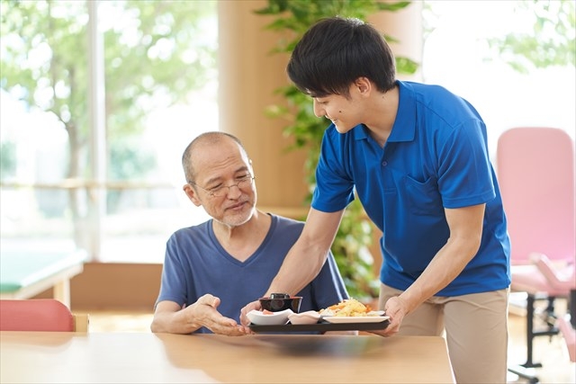 高齢者に配膳をする介護士