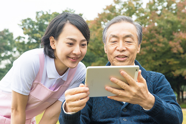 特養介護士がタブレットを一緒に見ながら利用者様と話をしている写真